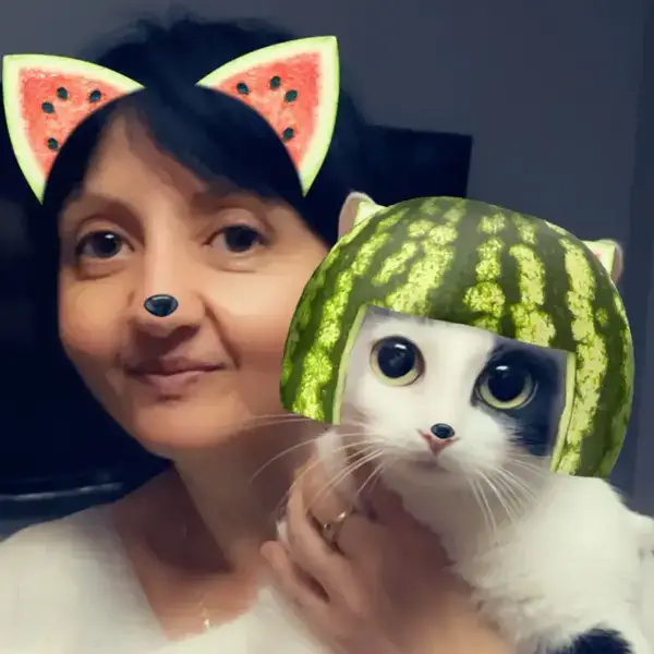 A person and a cat both wearing playful watermelon-themed filters; the person has watermelon ears, and the cat has a watermelon helmet.